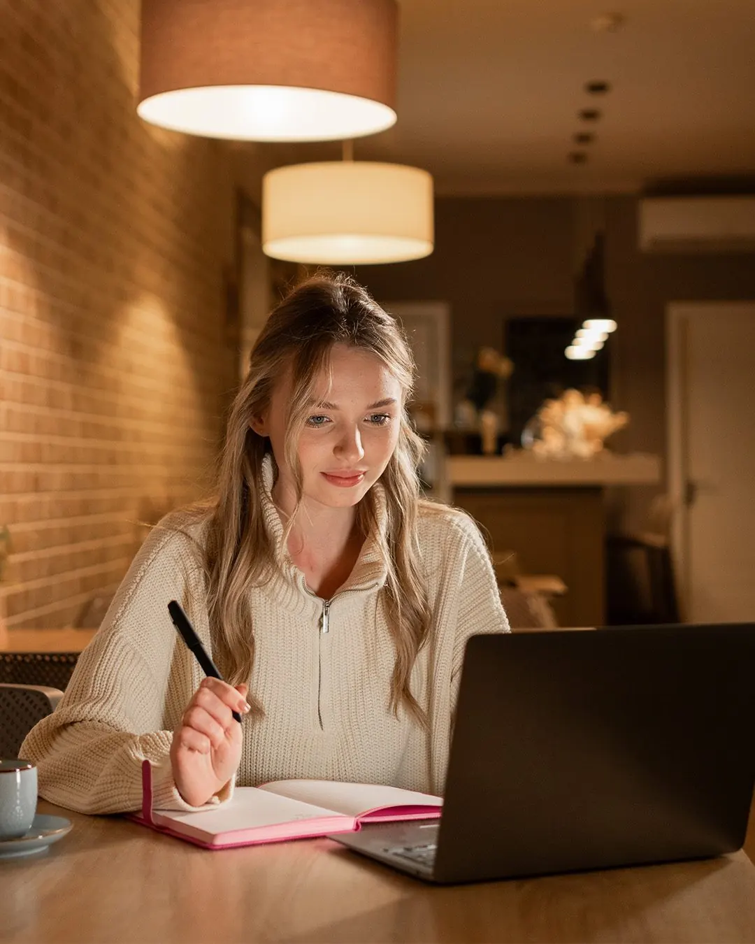 Aluna estudando inglês à noite com notebook e caderno